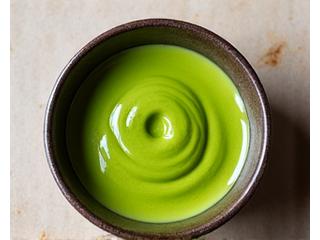 A beautifully whisked bright green ceremonial matcha tea in a traditional bowl.